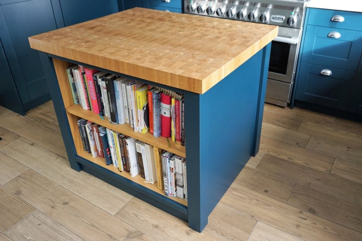 a wooden butchers block kitchen isalnd unit with books on it
