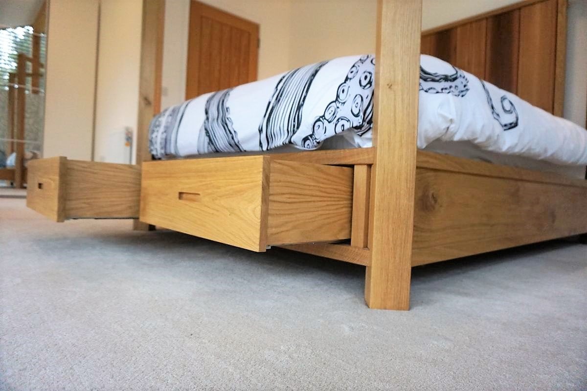 a four poster bed with underbed oak dovetails drawers on it