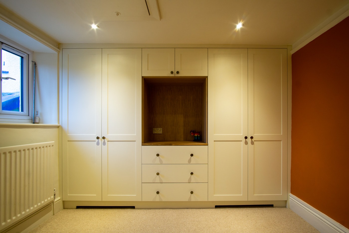 a room with white shaker wardrobe cabinets and a shelf