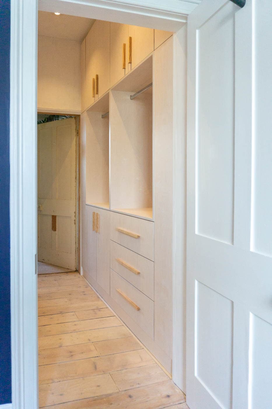 a hallway with white cabinets and drawers