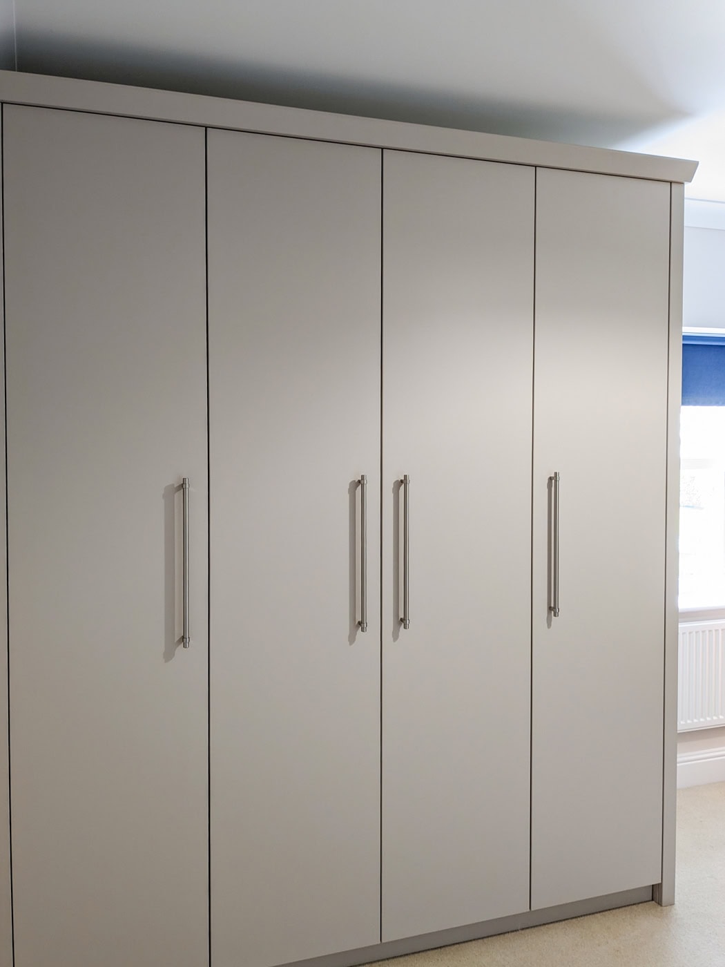 Bespoke fitted wardrobe in Winterbourne, near Bristol, featuring a simple yet elegant design with a Farrow & Ball Roasted Macadamia finish, four interior drawers on full extension soft close runners, and ample hanging space with sleek, simple handles.