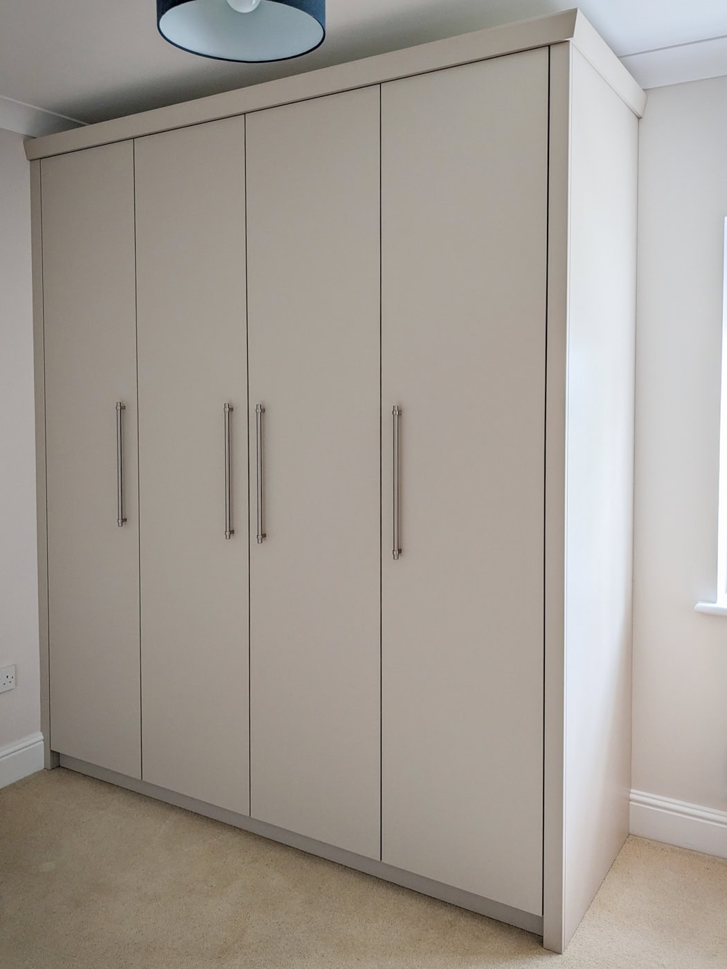 Bespoke tall fitted wardrobe in Winterbourne, near Bristol, featuring a simple yet elegant design with a Farrow & Ball Roasted Macadamia finish, four interior drawers on full extension soft close runners, and ample hanging space with sleek, simple handles.