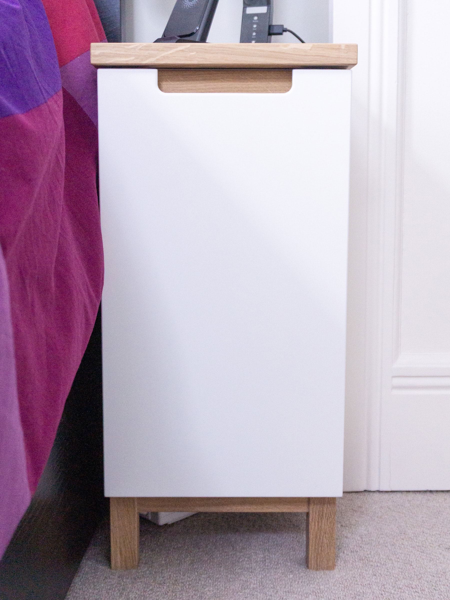 a white bedside table with a handle