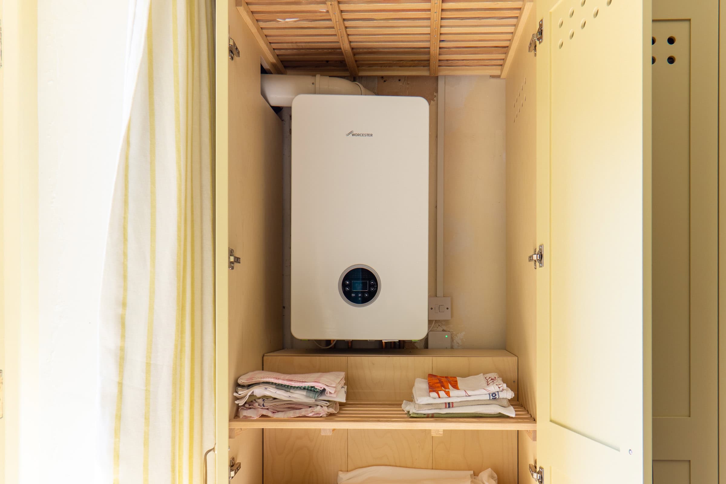 interior of a bespoke airing cupboard showing the boiler plywood interior and vent holes