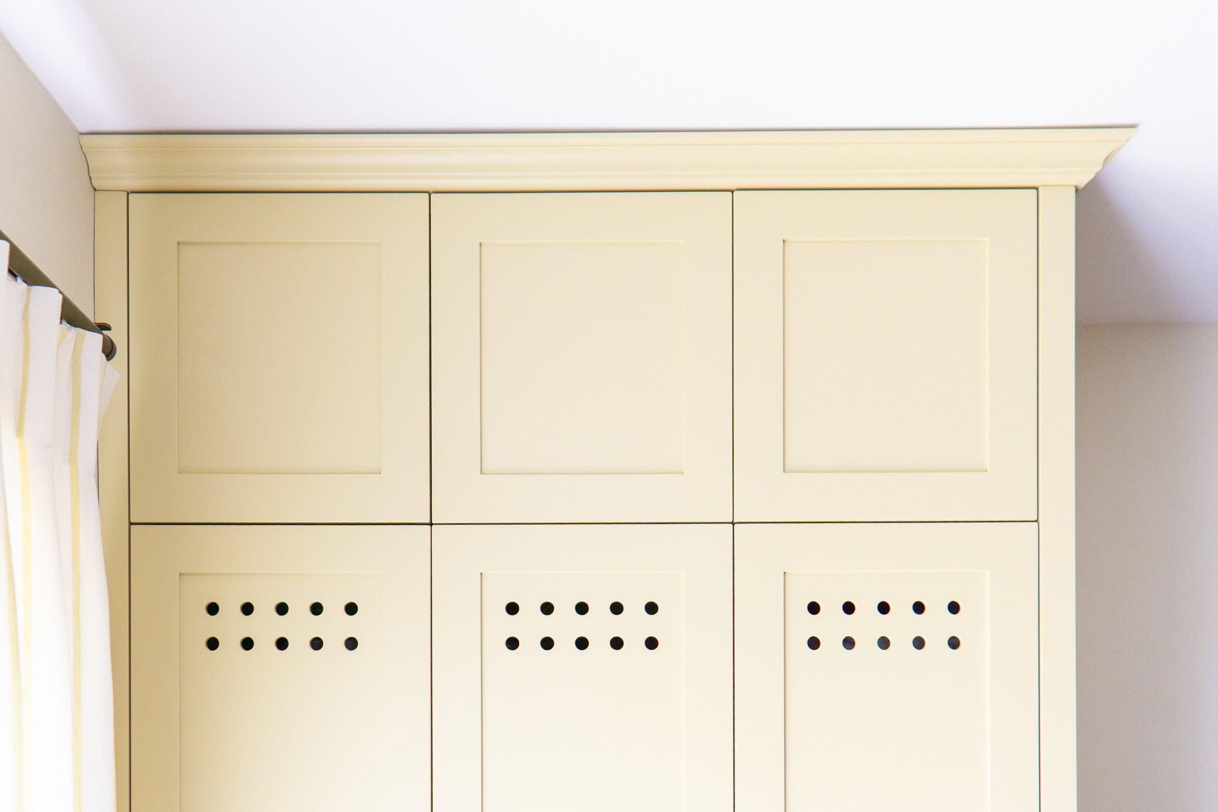 shaker style bespoke wardrobe with vented doors and cornice in a bright room